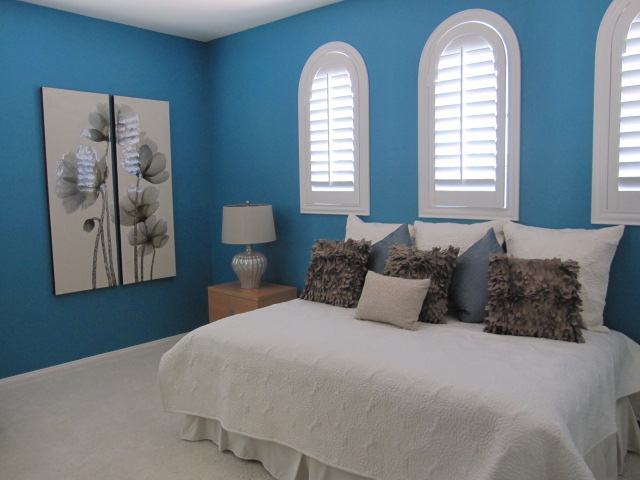 Blue bedroom with white plantation shutters.